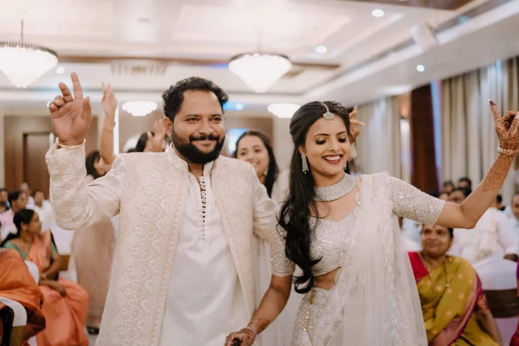 Photographers in Mysore capturing an exciting wedding entry with the couple dancing, friends following behind in celebration.