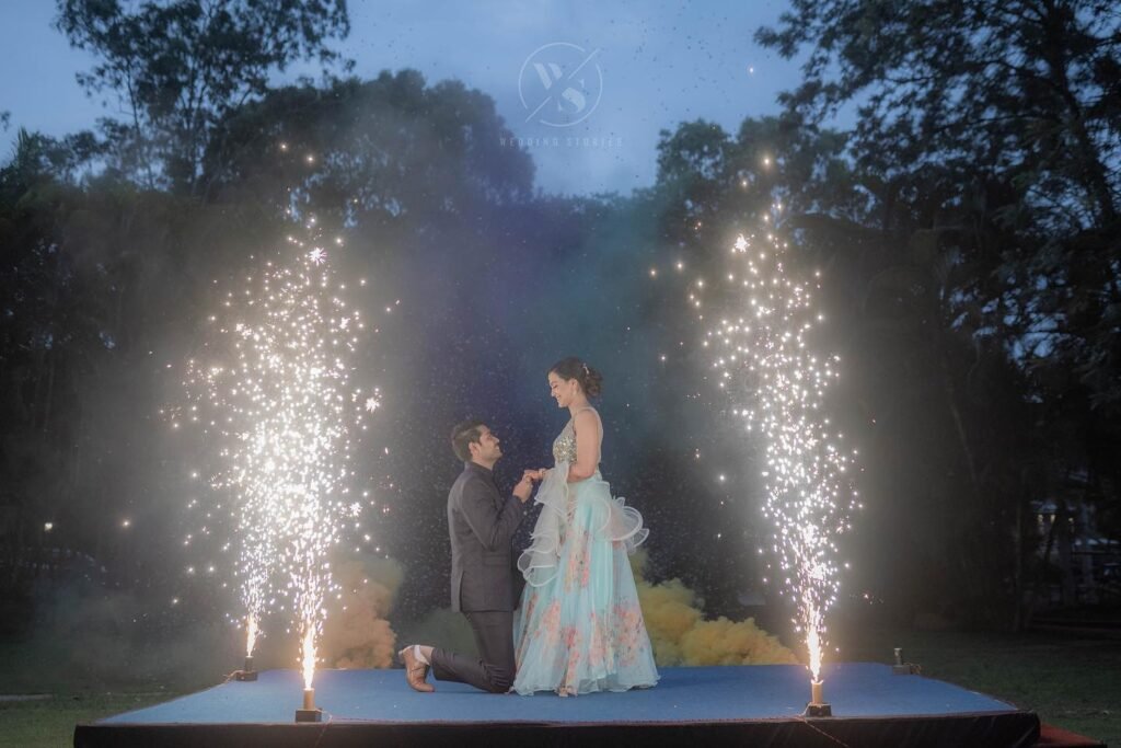 Chethan & Aishwarya night outdoor shoot with groom on one knee holding bride’s hand as cold pyro effects light up