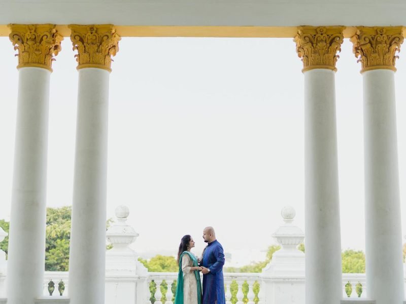 Bride and groom in casual Indian wear at white palace in a wide horizontal shot capturing the beauty of the palace