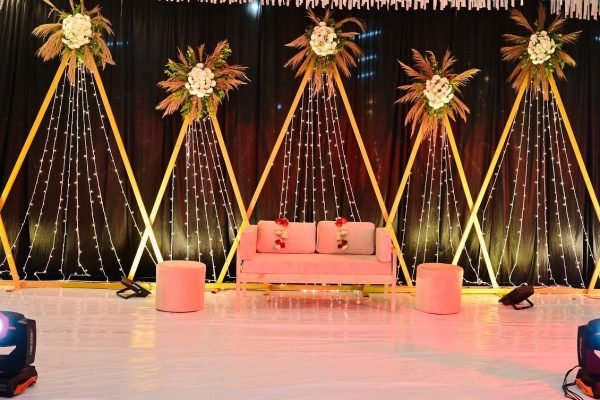 Event Management in Mysore by Wedding Stories — wedding reception stage with white bride and groom seating, golden background décor, and elegant props.